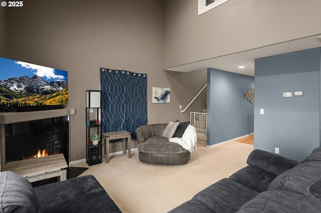 carpeted living room with baseboards, a high ceiling, and a tiled fireplace