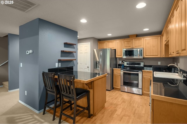 kitchen featuring visible vents, a sink, open shelves, appliances with stainless steel finishes, and a peninsula