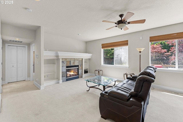 11168 SW Brown St, Tualatin, OR 97062 - living room featuring carpet floors, a ceiling fan, baseboards, a textured ceiling, and a tile fireplace