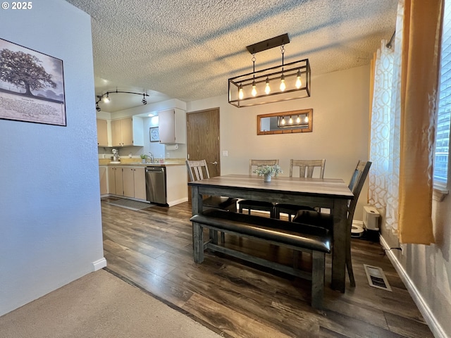 160 Heather Dr, Stanfield, OR 97875 - dining space with dark wood-style floors, a textured ceiling, rail lighting, and baseboards