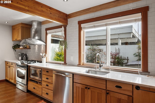 kitchen with wall chimney exhaust hood, sink, appliances with stainless steel finishes, dark hardwood / wood-style flooring, and light stone countertops