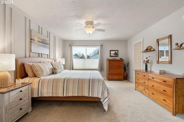 bedroom featuring ceiling fan, light colored carpet, and a textured ceiling