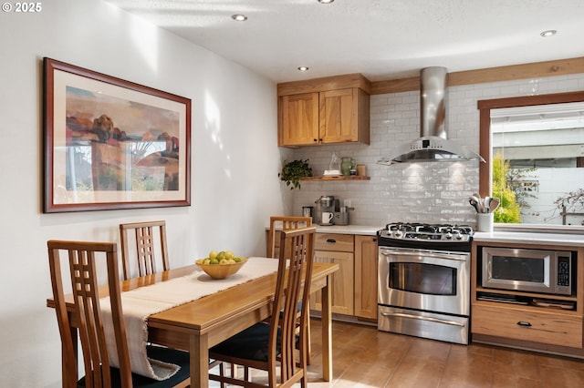 kitchen featuring wall chimney range hood, decorative backsplash, and stainless steel appliances