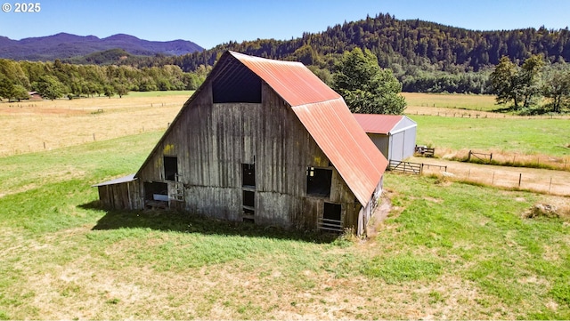 view of outbuilding featuring a rural view, a mountain view, and a yard