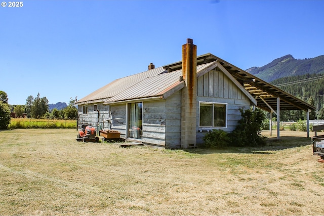 rear view of house featuring a mountain view and a yard