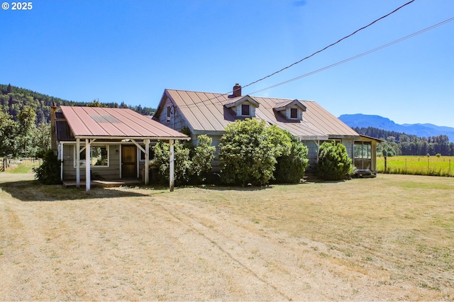 view of front facade featuring a mountain view, covered porch, and a front yard