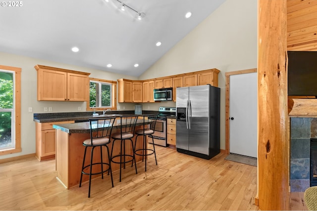1430 N Cedar Creek Cir, Rockaway Beach, OR 97136 - kitchen featuring stainless steel appliances, a kitchen breakfast bar, light wood-style floors, light brown cabinetry, and dark countertops