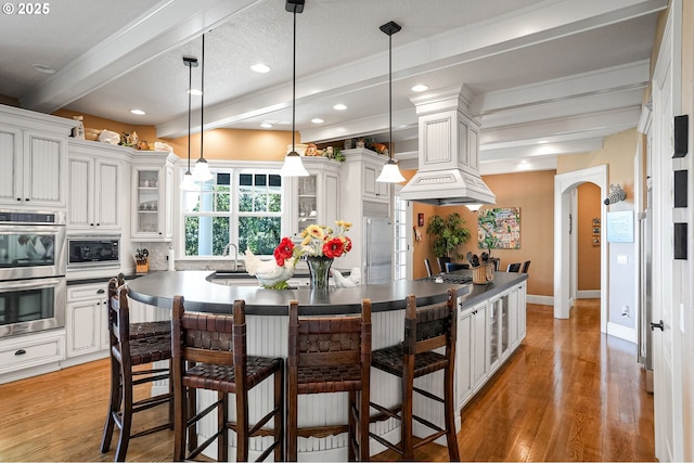 3545 Eagle Crest Rd NW, Salem, OR 97304 - kitchen featuring built in appliances, a center island, beam ceiling, arched walkways, and light wood-style flooring