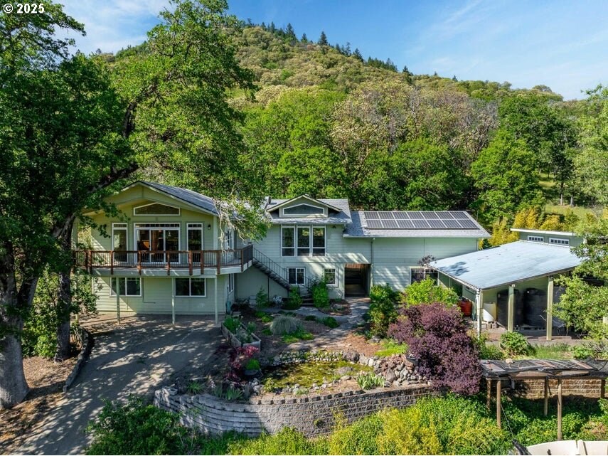 2583 E Evans Creek Rd, Rogue River, OR 97537 - rear view of property with stairs, a wooded view, solar panels, and a deck