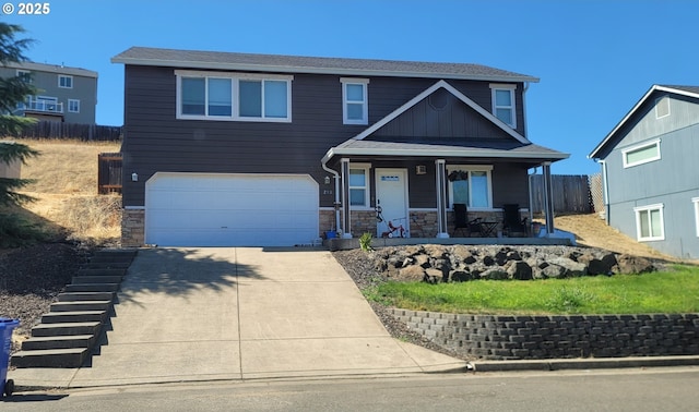 view of front of property featuring fence, a porch, a garage, stone siding, and driveway