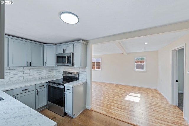 1751 S 19th St, Coos Bay, OR 97420 - kitchen with light wood finished floors, baseboards, beamed ceiling, appliances with stainless steel finishes, and tasteful backsplash