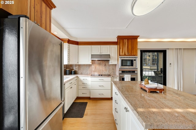 kitchen featuring appliances with stainless steel finishes, decorative backsplash, white cabinetry, and light stone counters