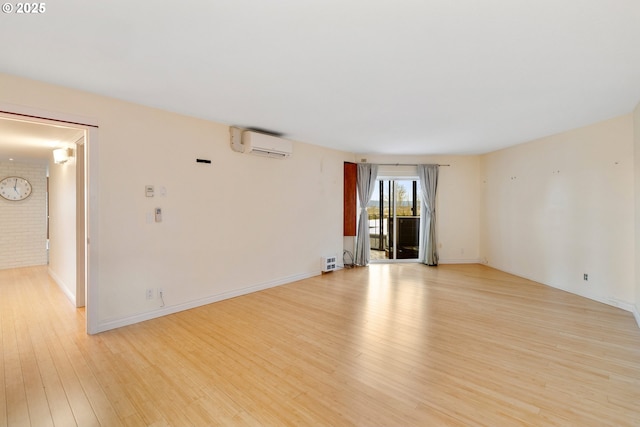 spare room with a wall unit AC and light wood-type flooring