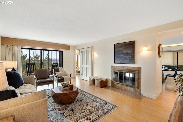 living room with a textured ceiling, a high end fireplace, and light hardwood / wood-style floors