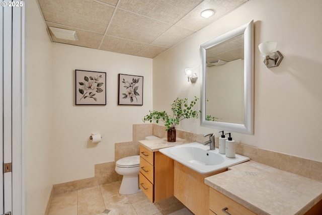 bathroom featuring tile patterned floors, toilet, vanity, and a paneled ceiling