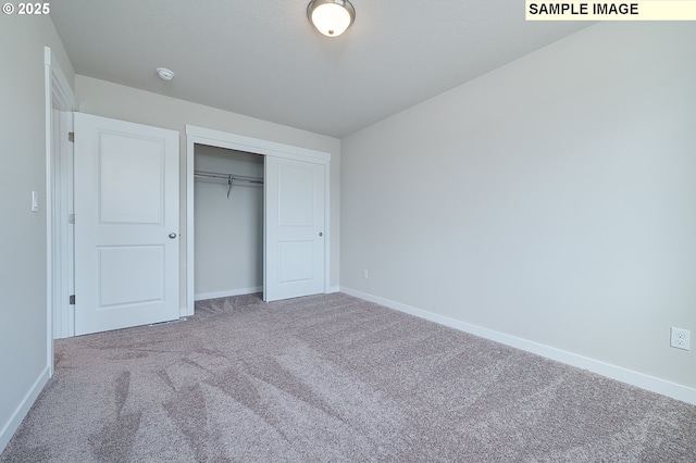 unfurnished bedroom with carpet, a closet, a textured ceiling, and baseboards