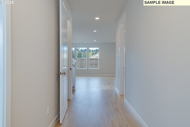 hallway featuring light wood-type flooring, baseboards, and recessed lighting