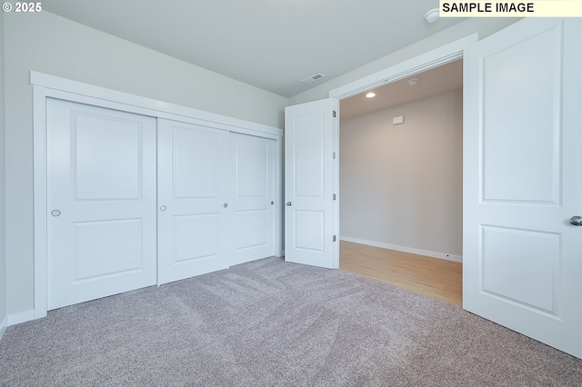 unfurnished bedroom featuring light carpet, a closet, visible vents, and baseboards