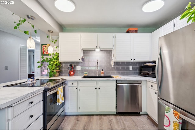 kitchen with light wood-style floors, a sink, backsplash, and stainless steel appliances