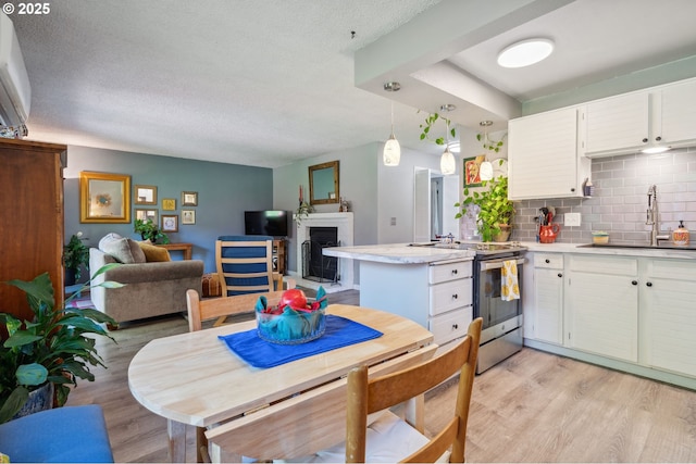 kitchen with a sink, stainless steel range with electric stovetop, light wood-style flooring, a peninsula, and white cabinetry
