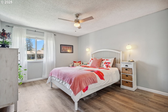 bedroom featuring a textured ceiling, baseboards, a ceiling fan, and wood finished floors