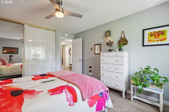 bedroom with heating unit, a textured ceiling, a ceiling fan, and wood finished floors