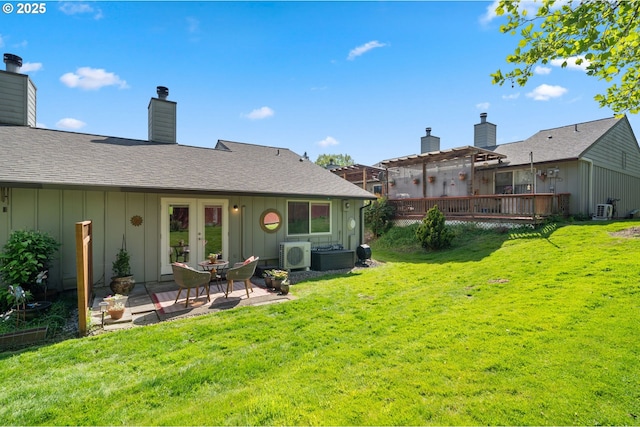 rear view of property featuring a lawn, board and batten siding, and a deck