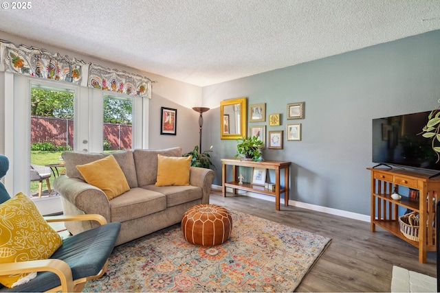 living room featuring baseboards, a textured ceiling, and wood finished floors