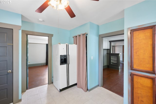 kitchen featuring light wood-style flooring, white fridge with ice dispenser, baseboards, and a ceiling fan