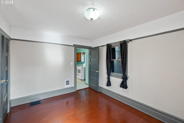 spare room with baseboards, a textured ceiling, visible vents, and dark wood-style flooring