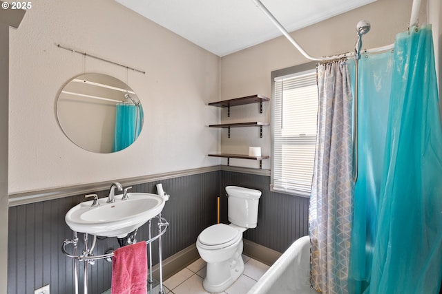 full bathroom with shower / bath combo, wainscoting, a sink, and tile patterned floors