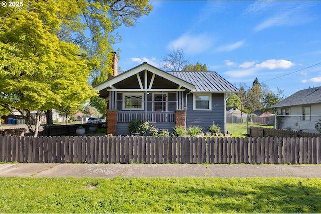 view of front of property with a standing seam roof, a fenced front yard, a porch, and metal roof