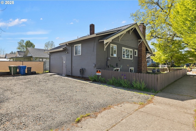 back of property featuring a chimney and fence