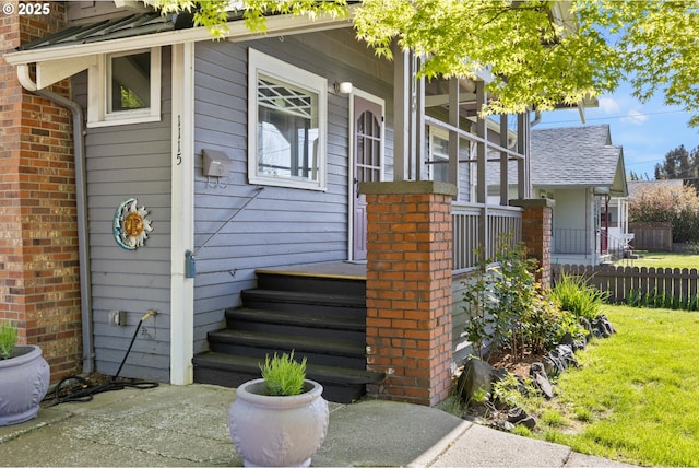 view of exterior entry with brick siding and fence