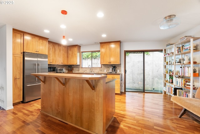 2345 NE Ridgewood Dr, Portland, OR 97212 - kitchen featuring high quality fridge, light wood finished floors, a kitchen breakfast bar, backsplash, and a sink