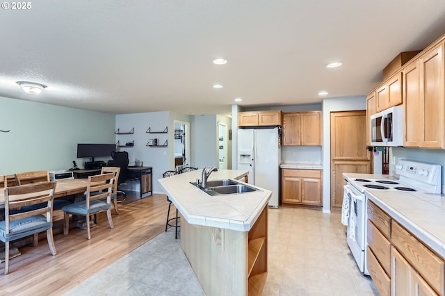 kitchen with white appliances, light brown cabinets, a sink, and tile countertops