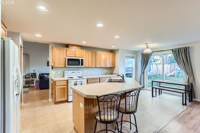 kitchen featuring tile countertops, recessed lighting, light brown cabinets, a sink, and white appliances