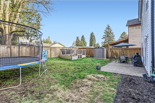 view of yard with a fenced backyard, an outbuilding, a trampoline, a storage unit, and a patio area