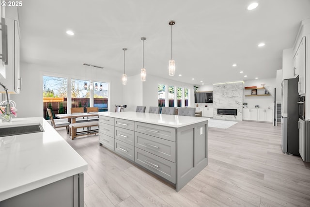 kitchen with recessed lighting, gray cabinetry, light countertops, and a sink