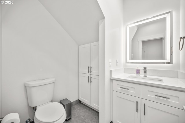 bathroom with toilet, vanity, and vaulted ceiling