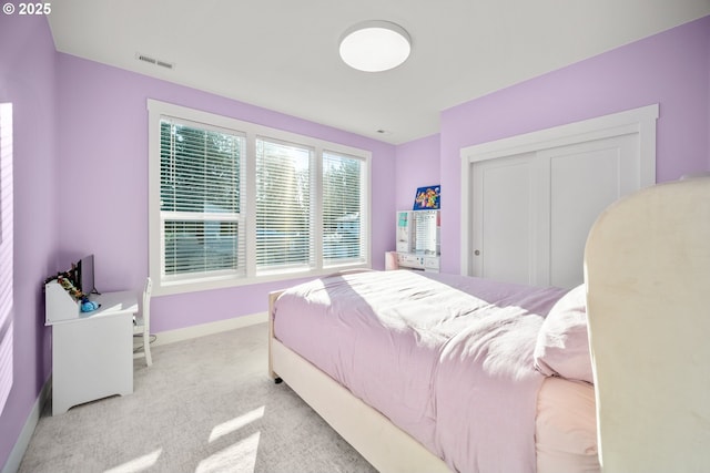 bedroom featuring visible vents, light colored carpet, and baseboards