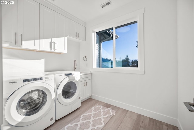 laundry area with visible vents, light wood-style flooring, cabinet space, a sink, and independent washer and dryer