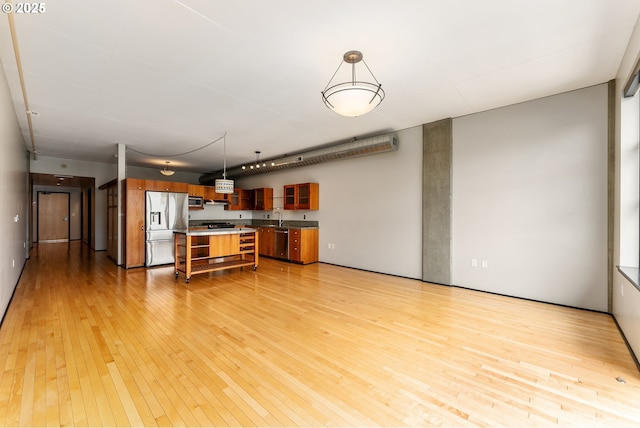 333 NW 9th Ave Unit 902, Portland, OR 97209 - kitchen featuring stainless steel appliances, light wood finished floors, brown cabinetry, a breakfast bar, and a sink