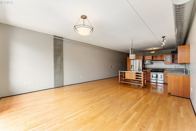 333 NW 9th Ave Unit 902, Portland, OR 97209 - kitchen featuring stainless steel appliances, light wood-style flooring, a sink, brown cabinetry, and hanging light fixtures