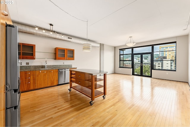 333 NW 9th Ave Unit 902, Portland, OR 97209 - kitchen featuring appliances with stainless steel finishes, a sink, brown cabinets, light wood-type flooring, and glass insert cabinets