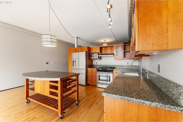 333 NW 9th Ave Unit 902, Portland, OR 97209 - kitchen with appliances with stainless steel finishes, a sink, brown cabinetry, light wood-style floors, and decorative light fixtures
