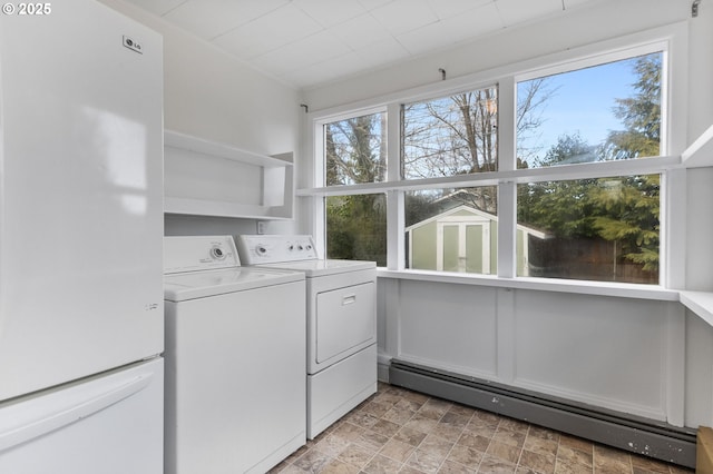 laundry area featuring a baseboard heating unit, washing machine and dryer, laundry area, and stone finish floor