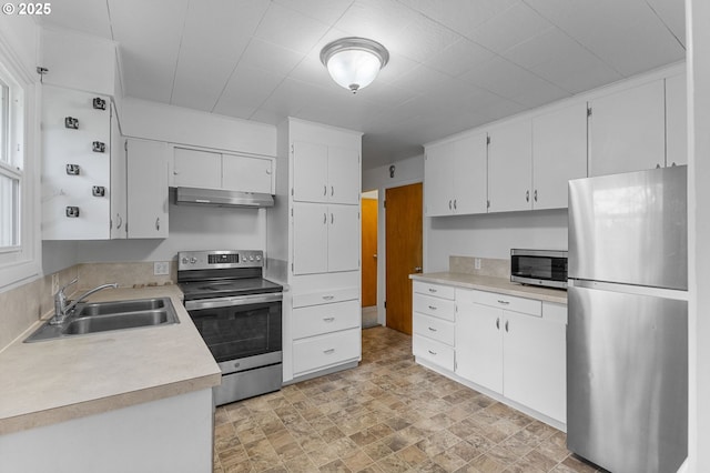 kitchen with under cabinet range hood, light countertops, white cabinets, stainless steel appliances, and a sink