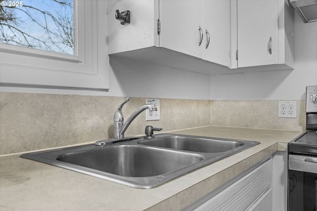 kitchen with ventilation hood, light countertops, decorative backsplash, white cabinets, and a sink