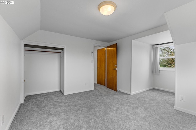 unfurnished bedroom with a closet, baseboards, carpet flooring, and vaulted ceiling